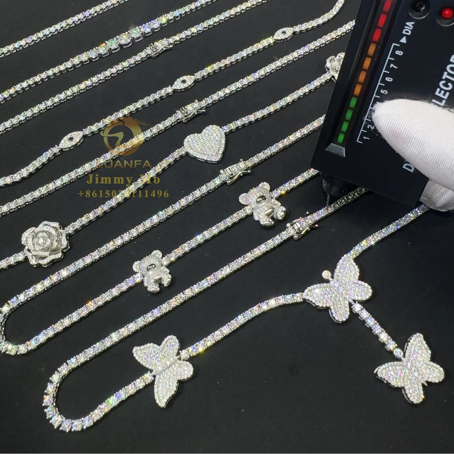 Jewelry with butterfly and flower designs being inspected by a gloved hand using a light source.