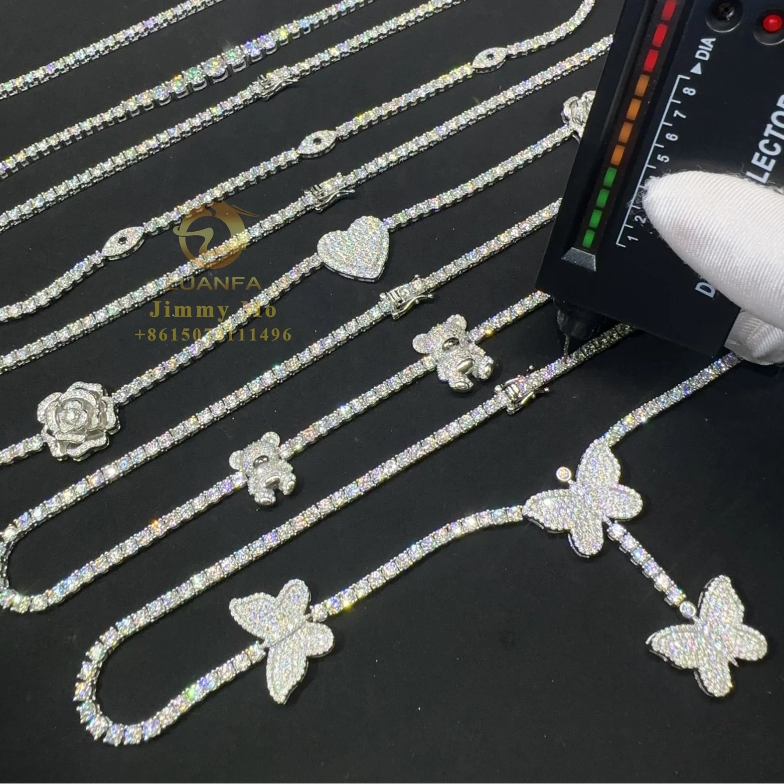 Jewelry with butterfly and flower designs being inspected by a gloved hand using a light source.
